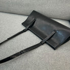 Black leather bag with a strap on a gray textured surface