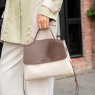 Person holding a two-toned handbag with a blurred background