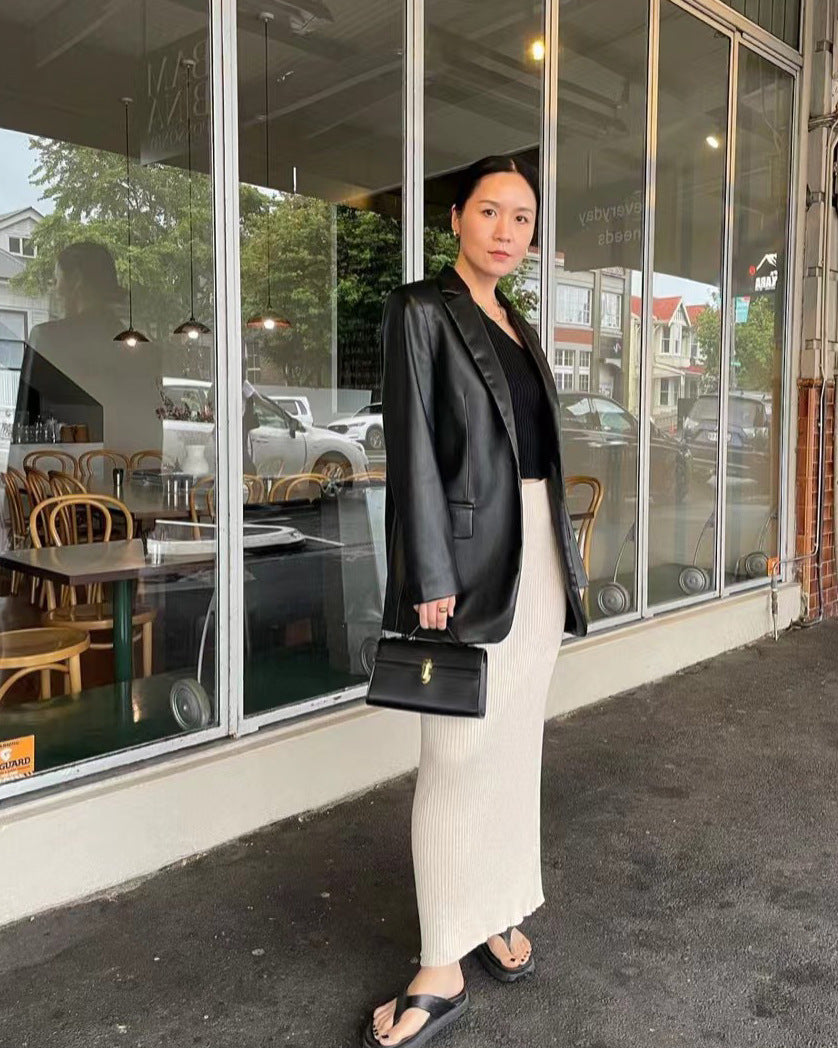 Woman in black blazer and white pants standing outside a cafe.