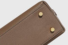 Close-up of a brown leather wallet with gold rivets on a light gray background