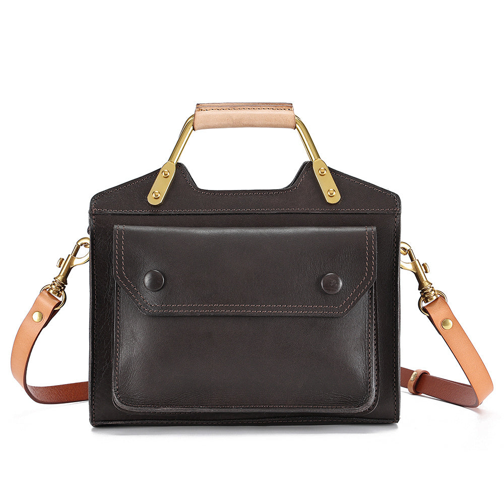 Black leather handbag with tan handle and strap on a white background