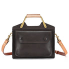 Black leather handbag with tan handle and strap on a white background