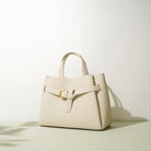 Beige handbag with a gold buckle on a light background