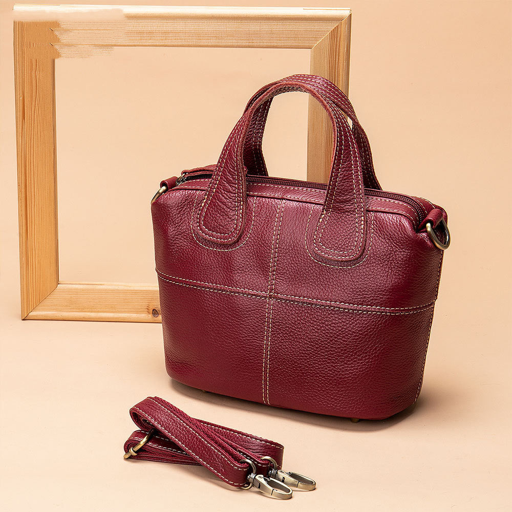Red handbag with detachable strap on a beige background