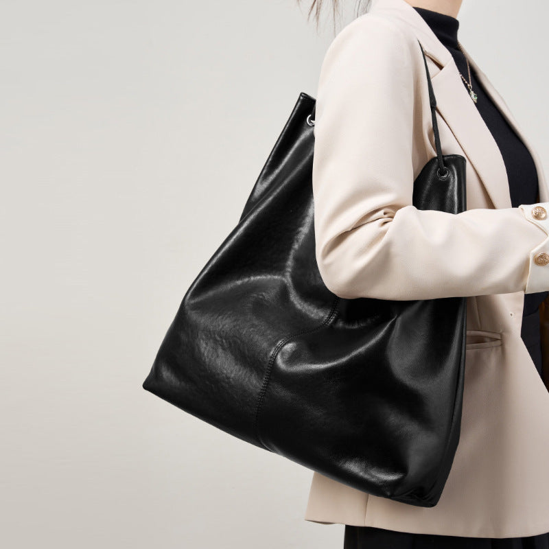 Person holding a black leather handbag against a plain background