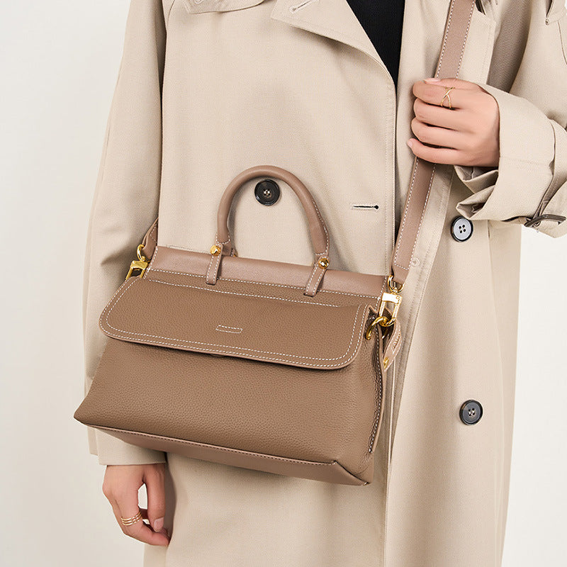 Person wearing a beige coat holding a matching beige handbag against a neutral background