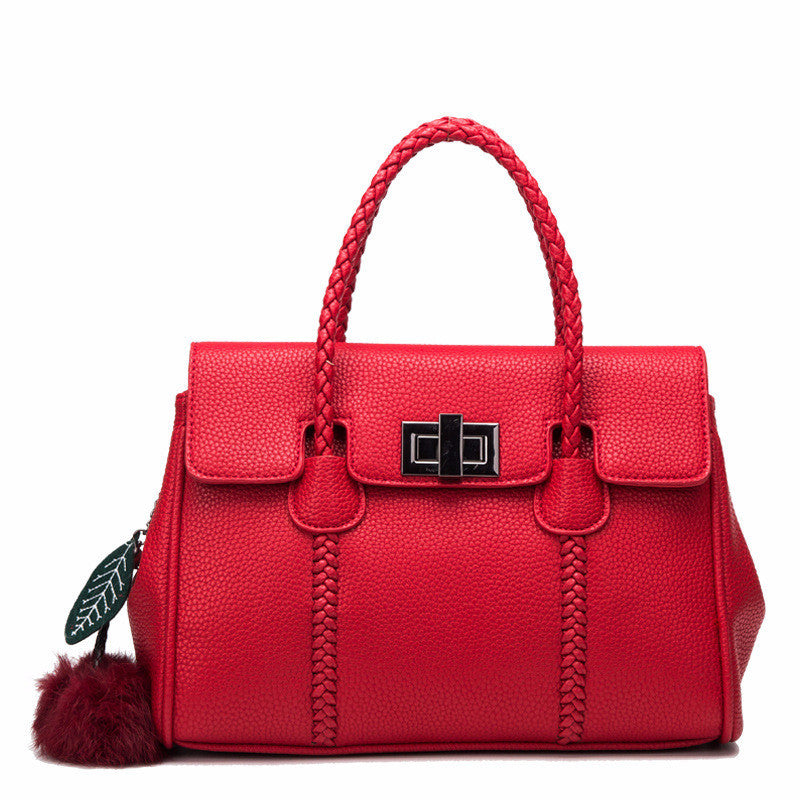 Red handbag with braided handle and decorative tag on a white background