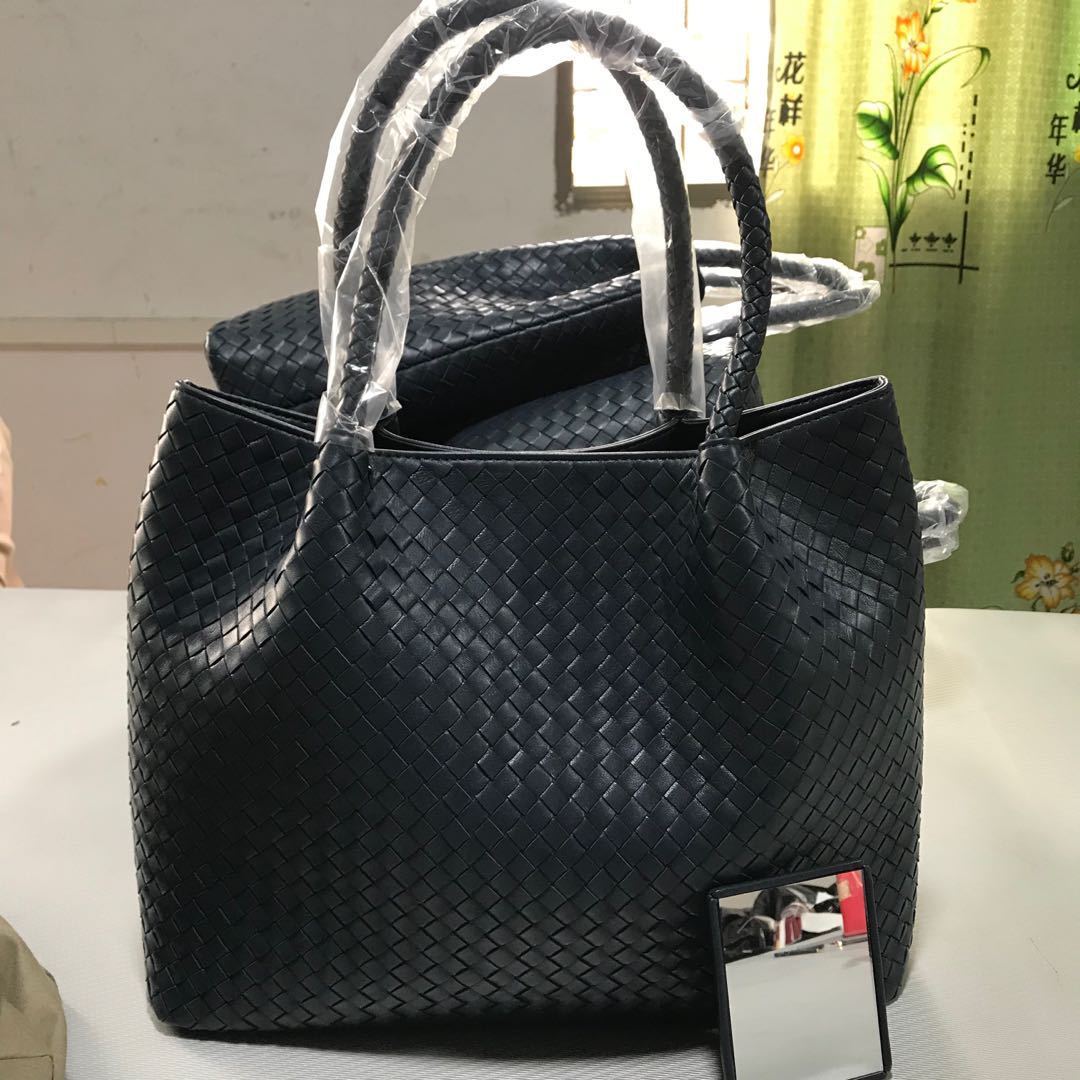 Black woven handbag on a white surface with a blurred background