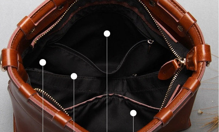 Brown leather bag with open top, showing interior and zippers.