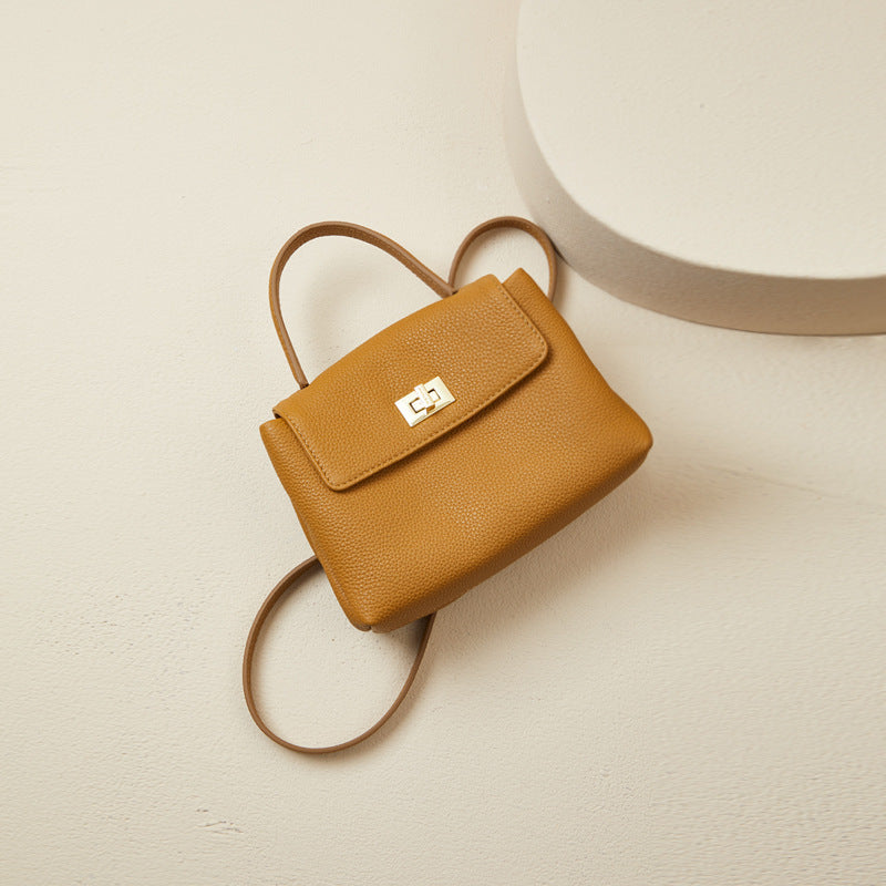 Brown leather backpack with a gold clasp on a beige background