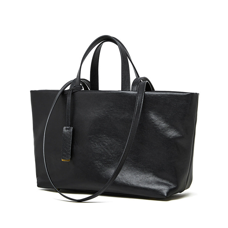 Black leather tote bag with shoulder strap on a white background