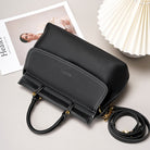Black handbag with gold accents on a light gray surface