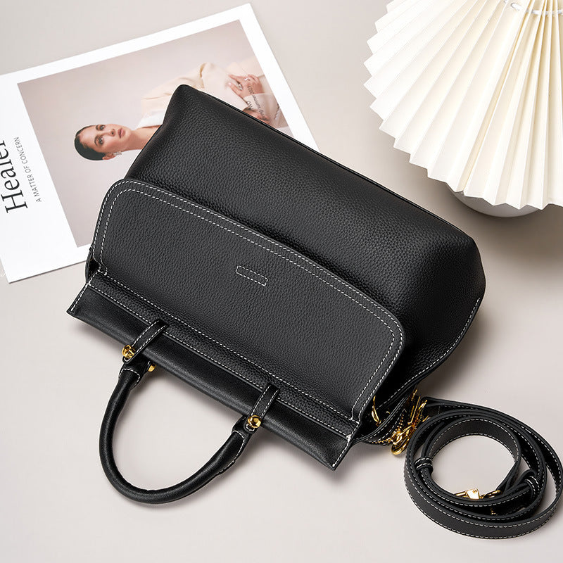Black handbag with gold accents on a light gray surface