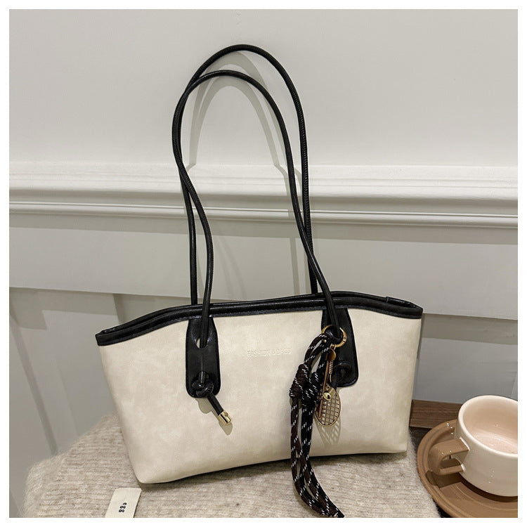 White handbag with black accents on a light gray surface