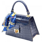 Navy blue handbag with gold accents and a blue scarf draped over it on a white background
