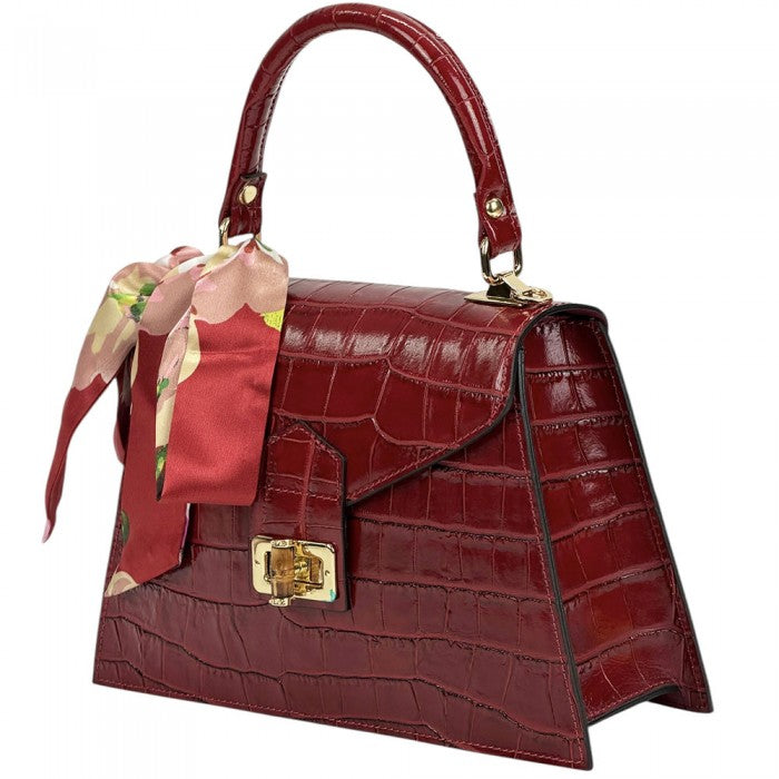 Red crocodile-patterned handbag with a floral scarf on a white background