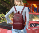 Person wearing a red backpack in front of a red car with a blurred background