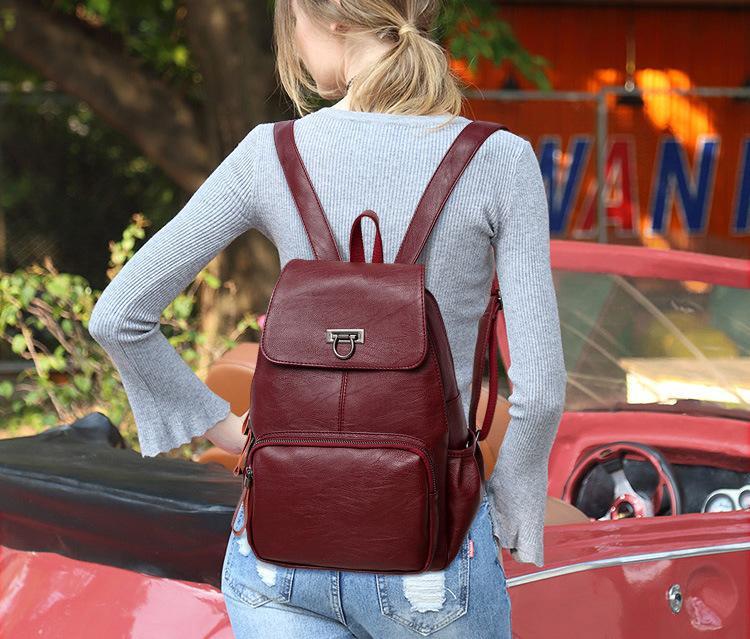 Person wearing a red backpack in front of a red car with a blurred background