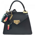 Black handbag with gold accents and colorful charms on a white background