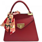 Red handbag with a floral scarf and gold accents on a white background