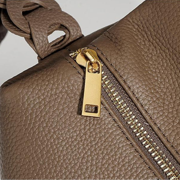 Close-up of a brown leather handbag with a gold zipper.