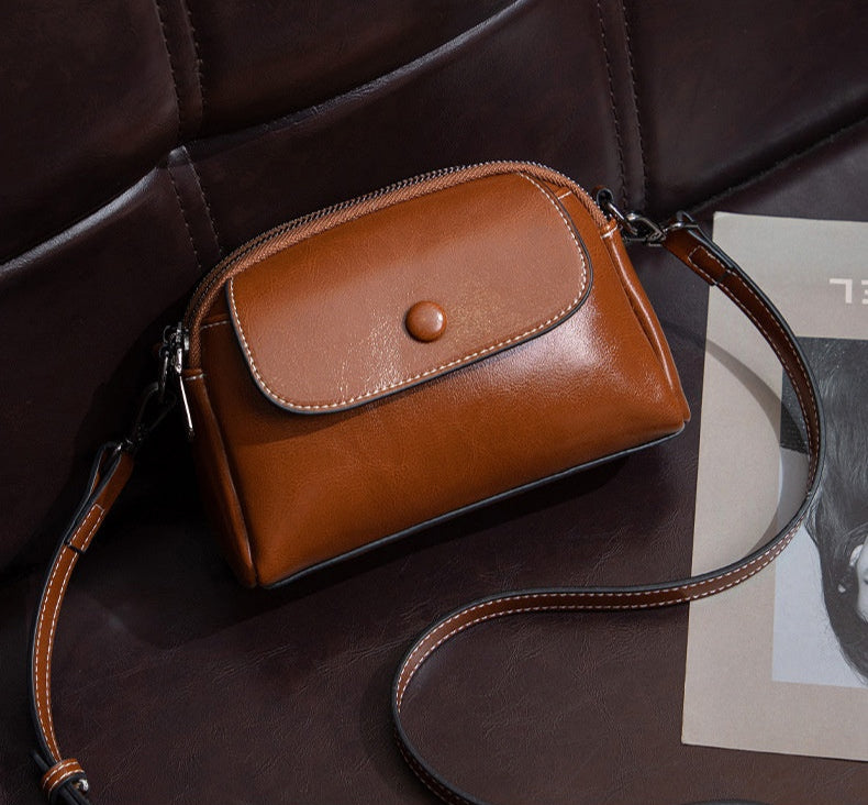 Brown leather handbag with a strap on a dark surface
