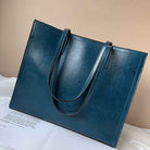 Blue leather tote bag on a white surface with a beige background