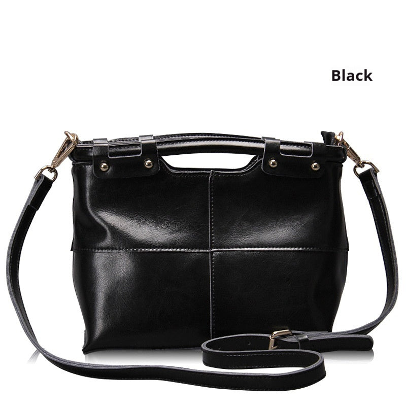 Black leather handbag with a shoulder strap on a white background