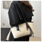 Person holding a beige handbag with black accents indoors