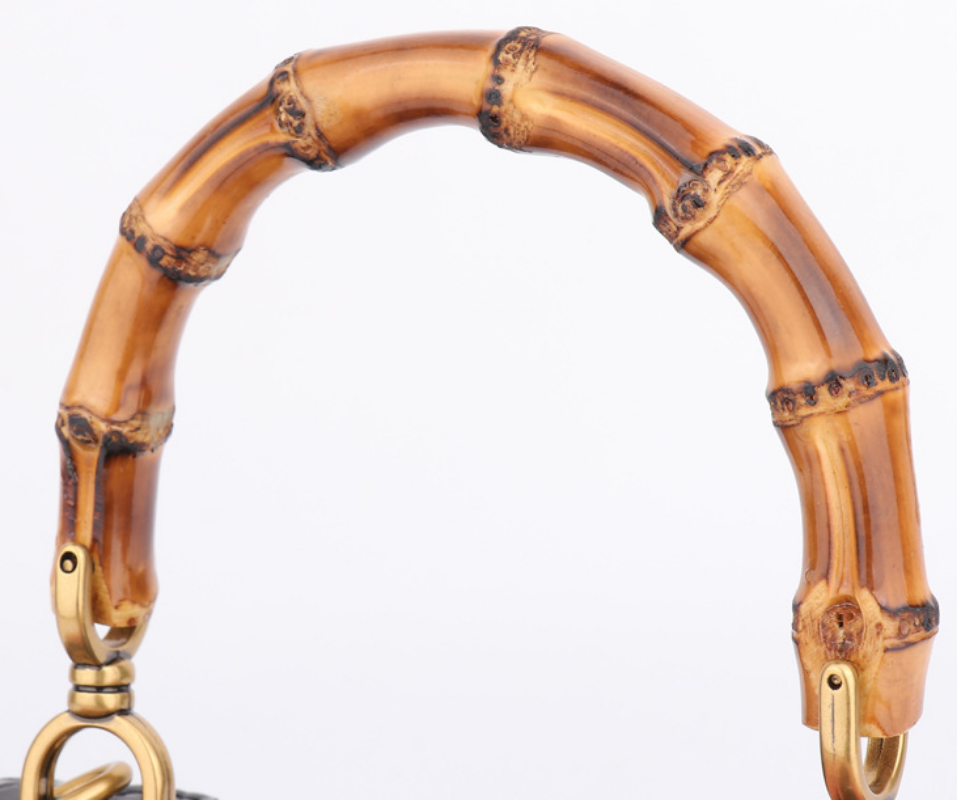Bamboo-shaped handbag handle with gold accents on a white background