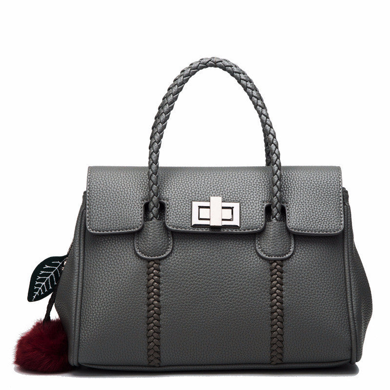 Gray handbag with braided handle and decorative pom-pom on a white background