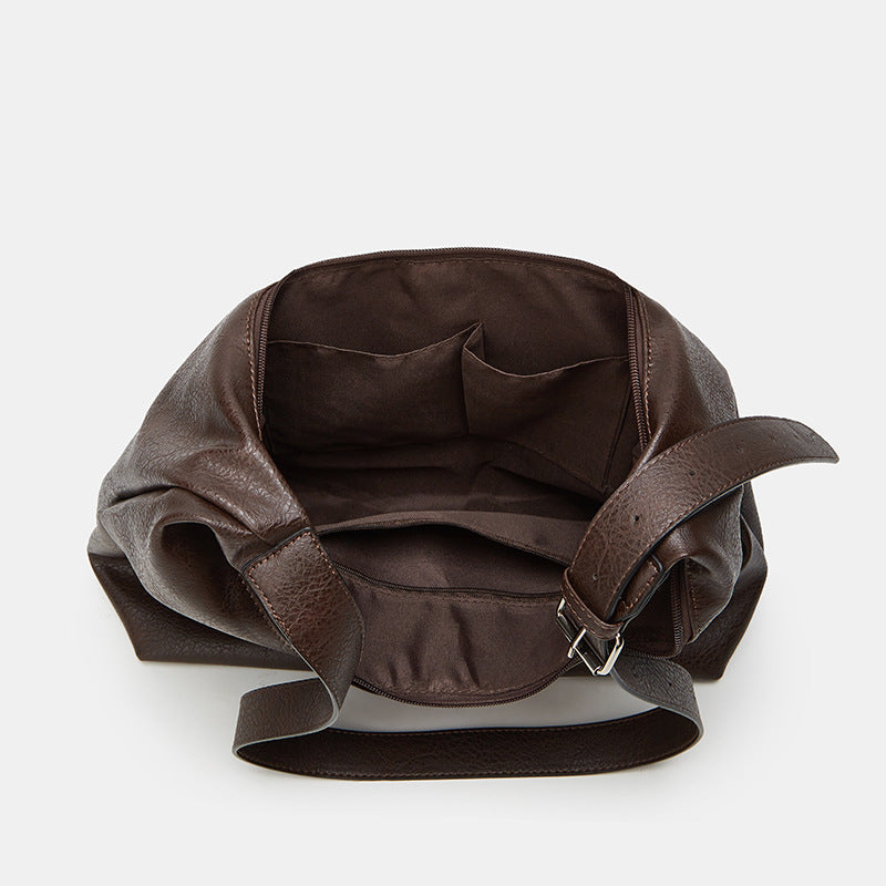 Brown leather handbag with a strap on a white background