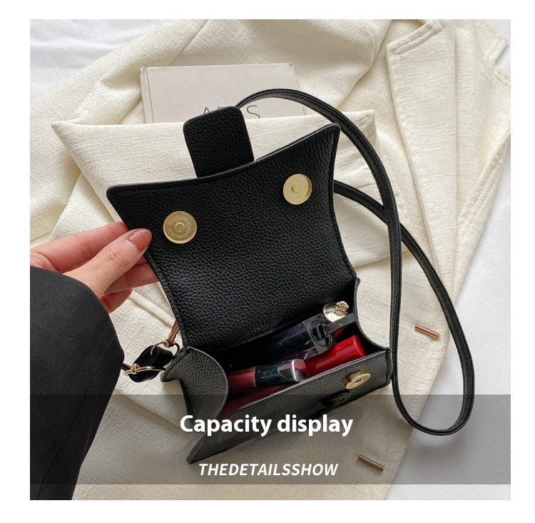 Black leather handbag with a capacity display feature, held by a hand on a light fabric background.