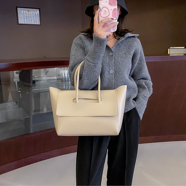Person holding a beige handbag in an indoor setting