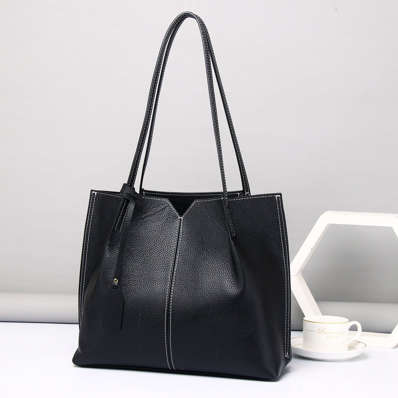Black leather tote bag on a light gray background