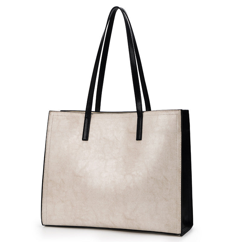 Beige handbag with black handles on a white background