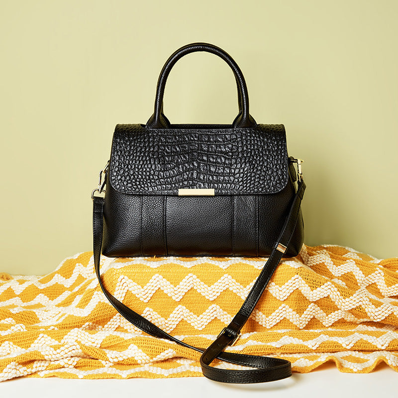 Black handbag on a yellow and white patterned fabric with a light green background