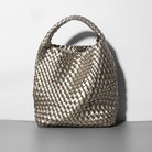 Woven handbag on a gray surface with a white background