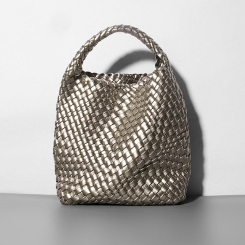 Woven handbag on a gray surface with a white background