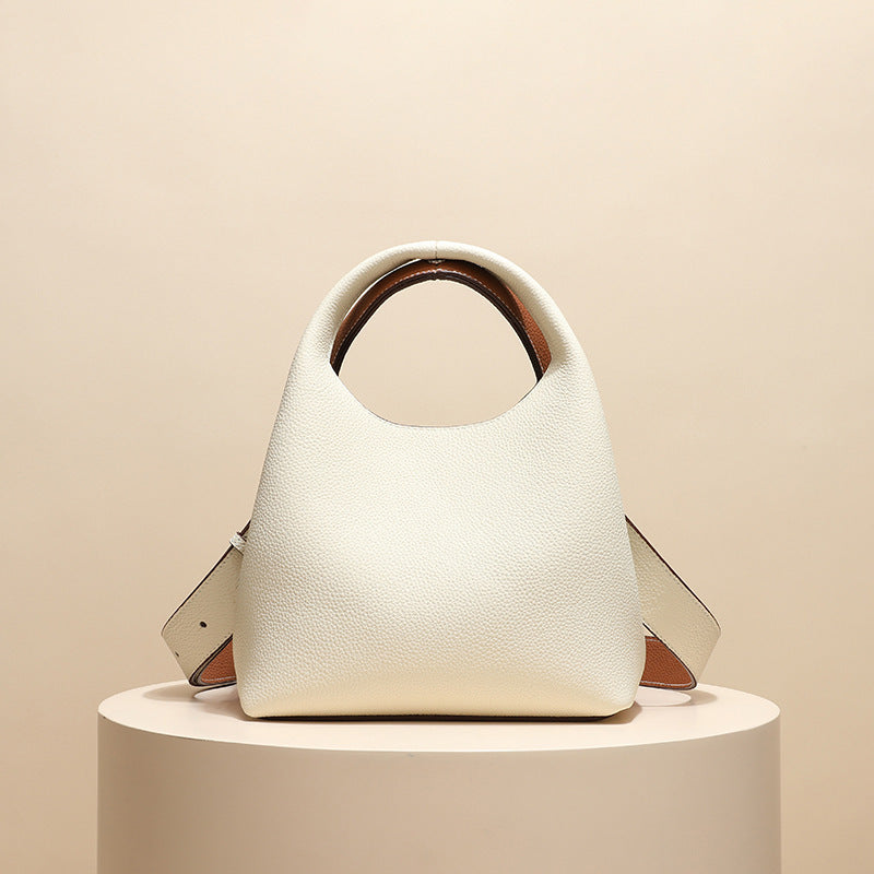 White handbag with brown accents on a beige background